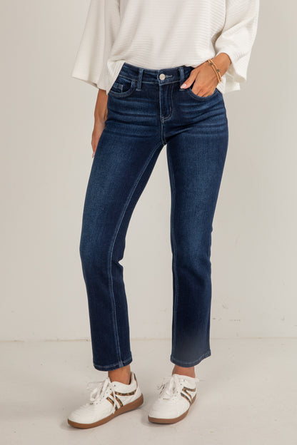 Person wearing blue jeans and white sneakers on a plain background