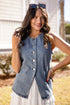 Woman wearing a denim vest over a white dress outdoors.