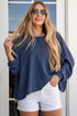 Woman wearing a blue top and white shorts standing in front of a glass door.