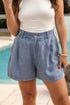 Person wearing blue shorts and a white top by a pool