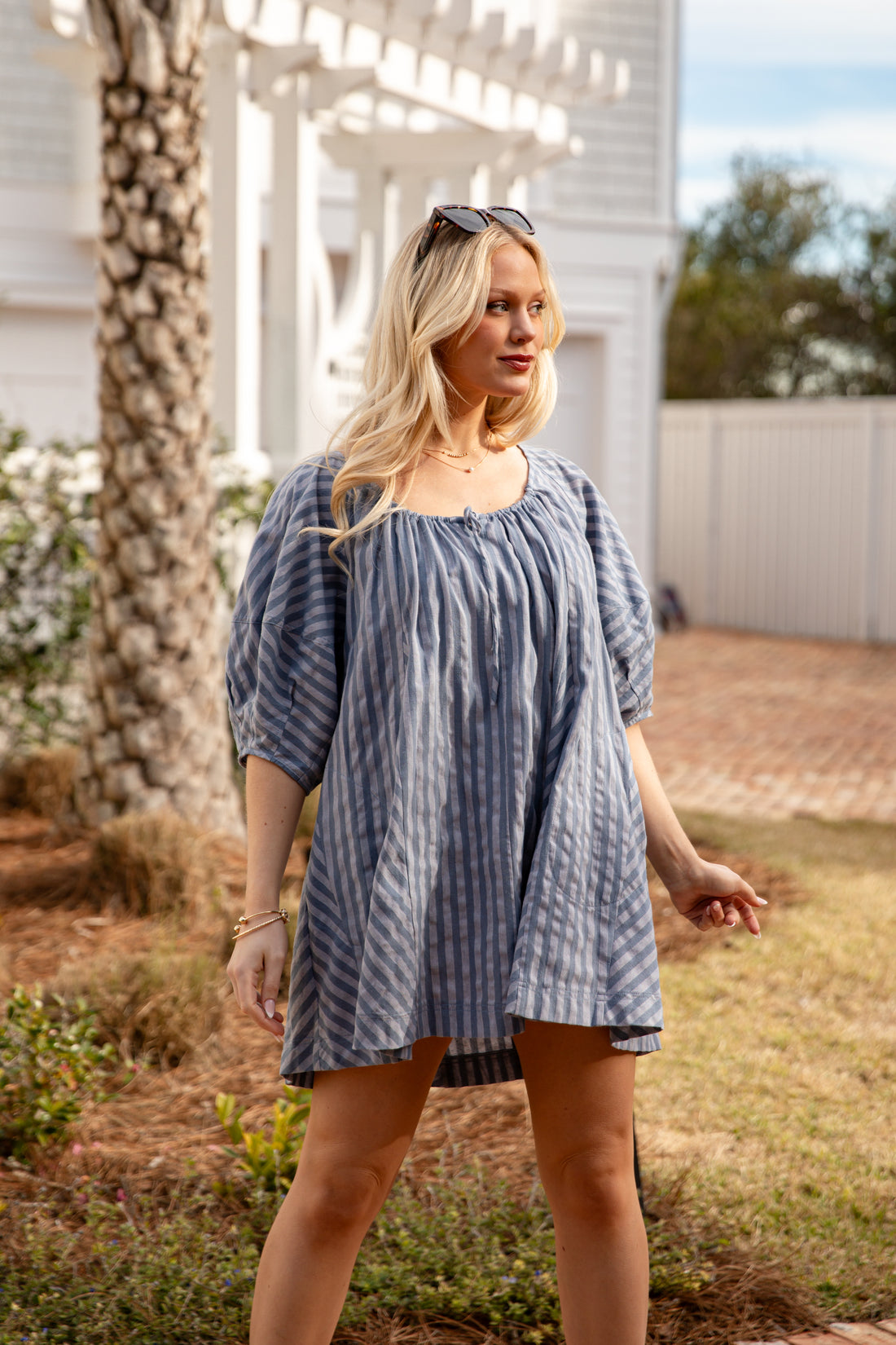 Woman wearing a blue striped dress standing outdoors.