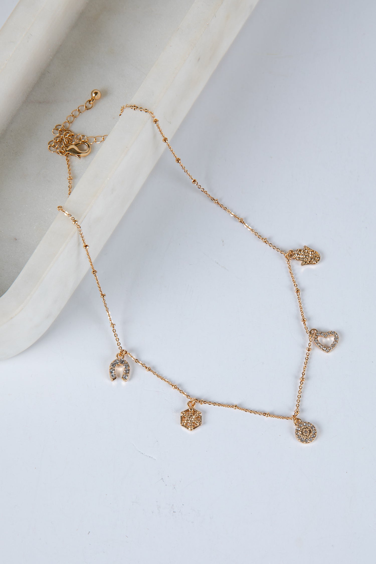 Gold necklace with heart-shaped pendants on a light gray background