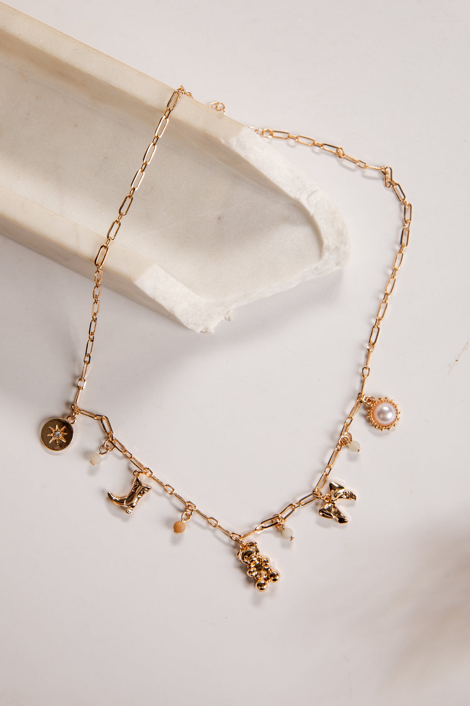 Gold necklace with charms on a white dish