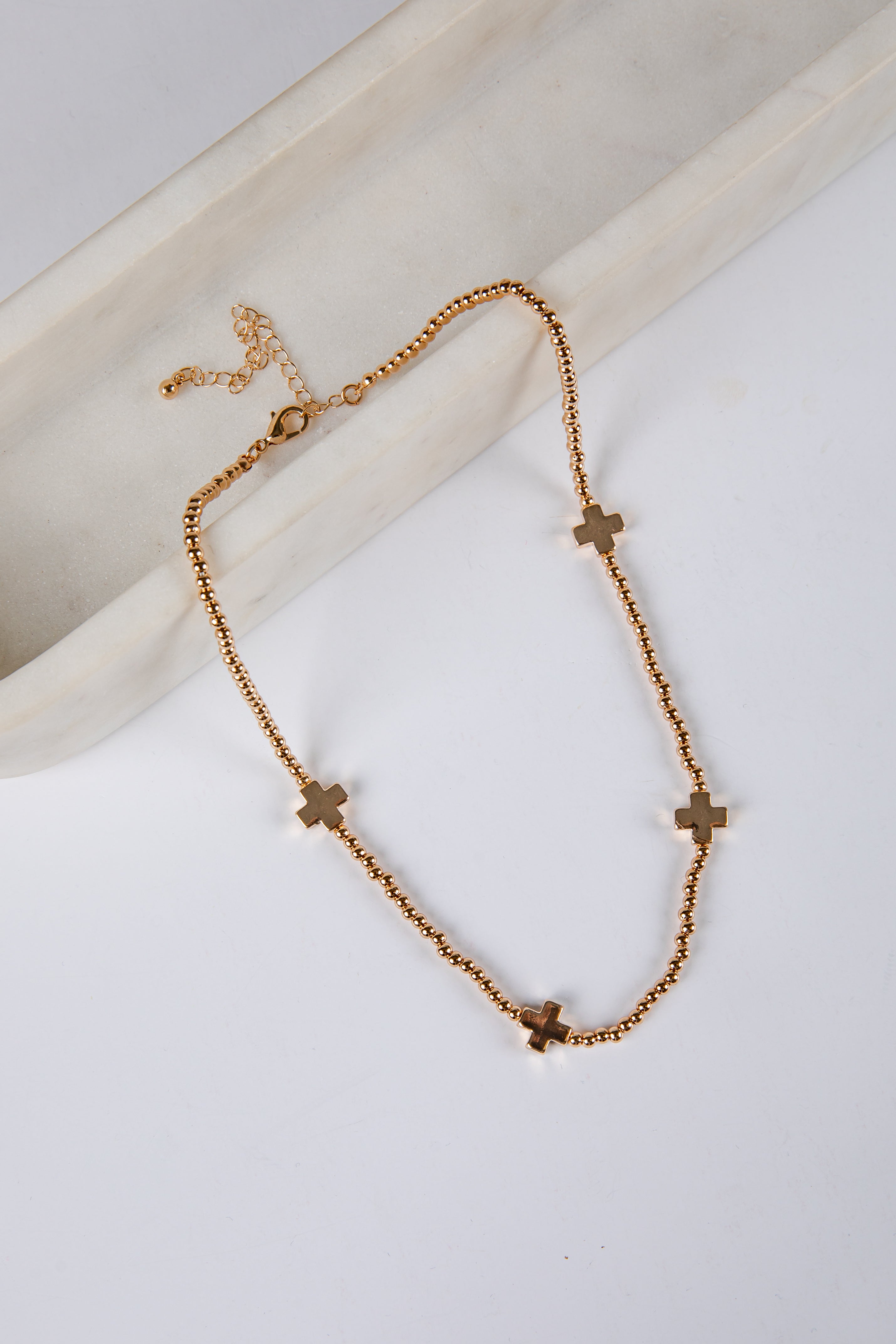 Gold necklace with cross pendants on a white surface
