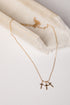 A delicate gold chain necklace with three small cross pendants, displayed on a light cream marble prop against a white background.