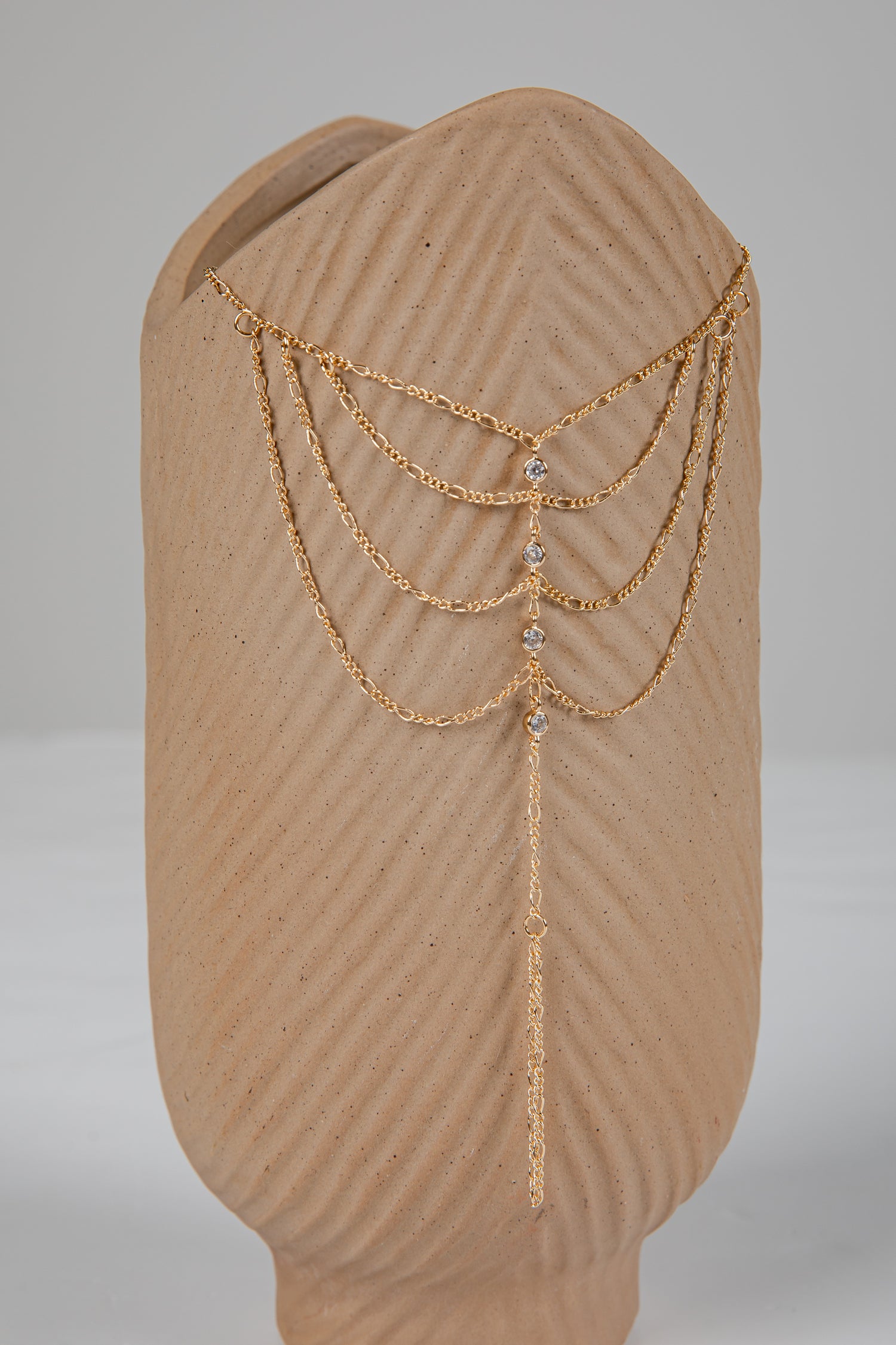 Gold chain headpiece on a mannequin head with a plain background