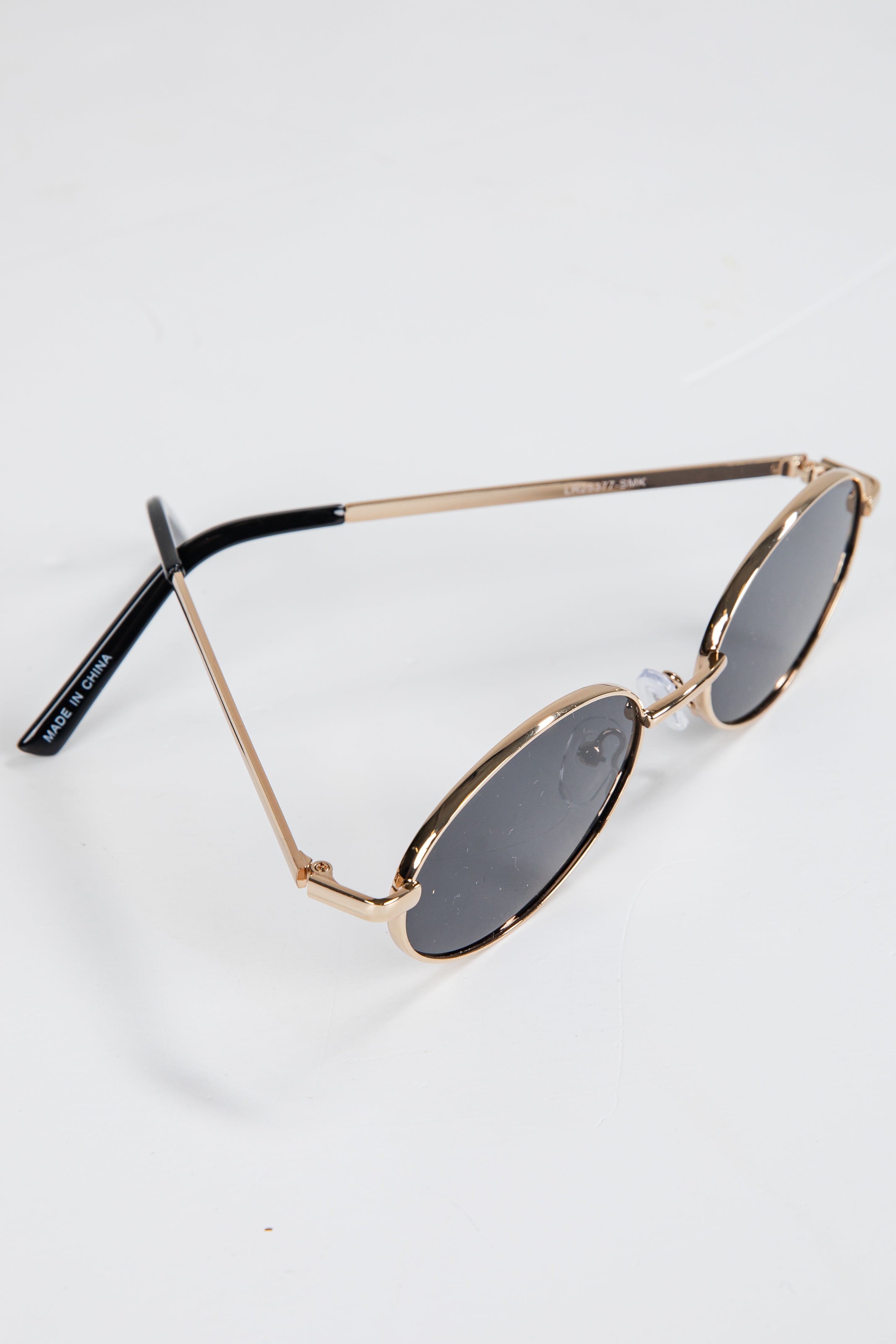 Gold-framed sunglasses with dark lenses on a white background