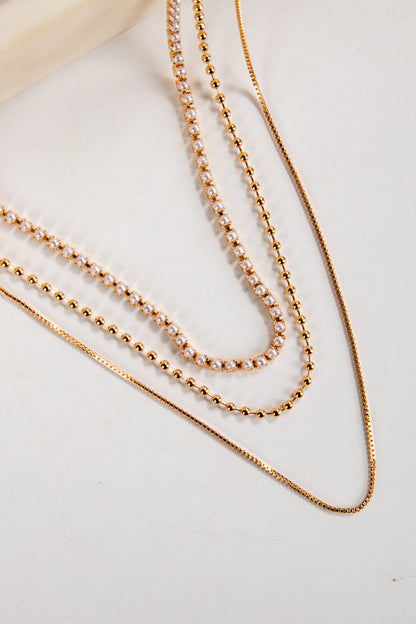 Three gold necklaces on a light background