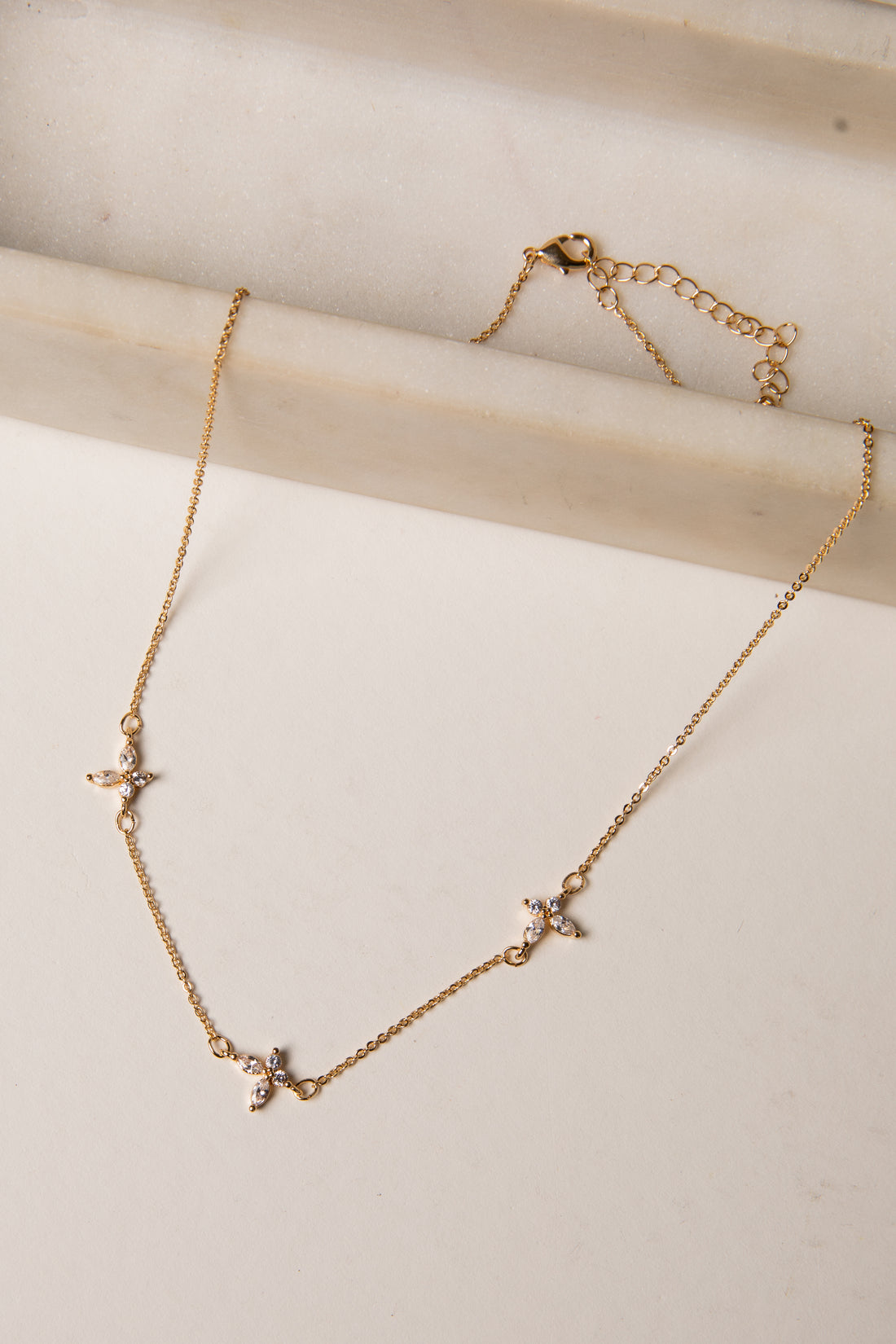Gold necklace with star-shaped pendants on a light wooden surface