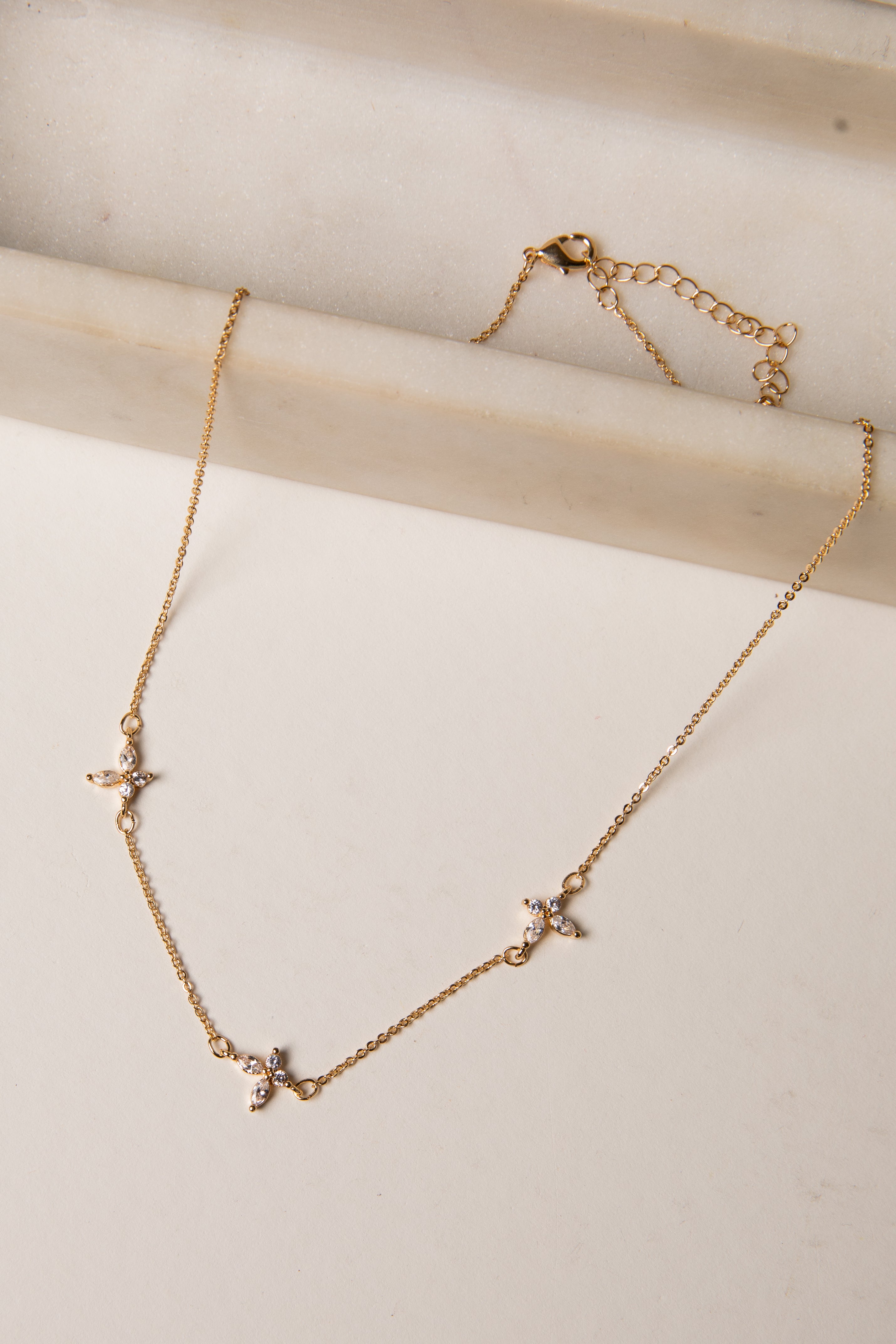 Gold necklace with star-shaped pendants on a light wooden surface