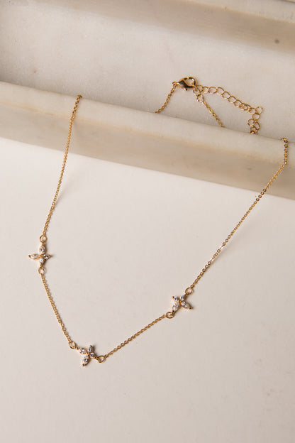 Gold necklace with star-shaped pendants on a light wooden surface