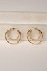 Gold hoop earrings with rhinestone detailing on a light wooden surface.