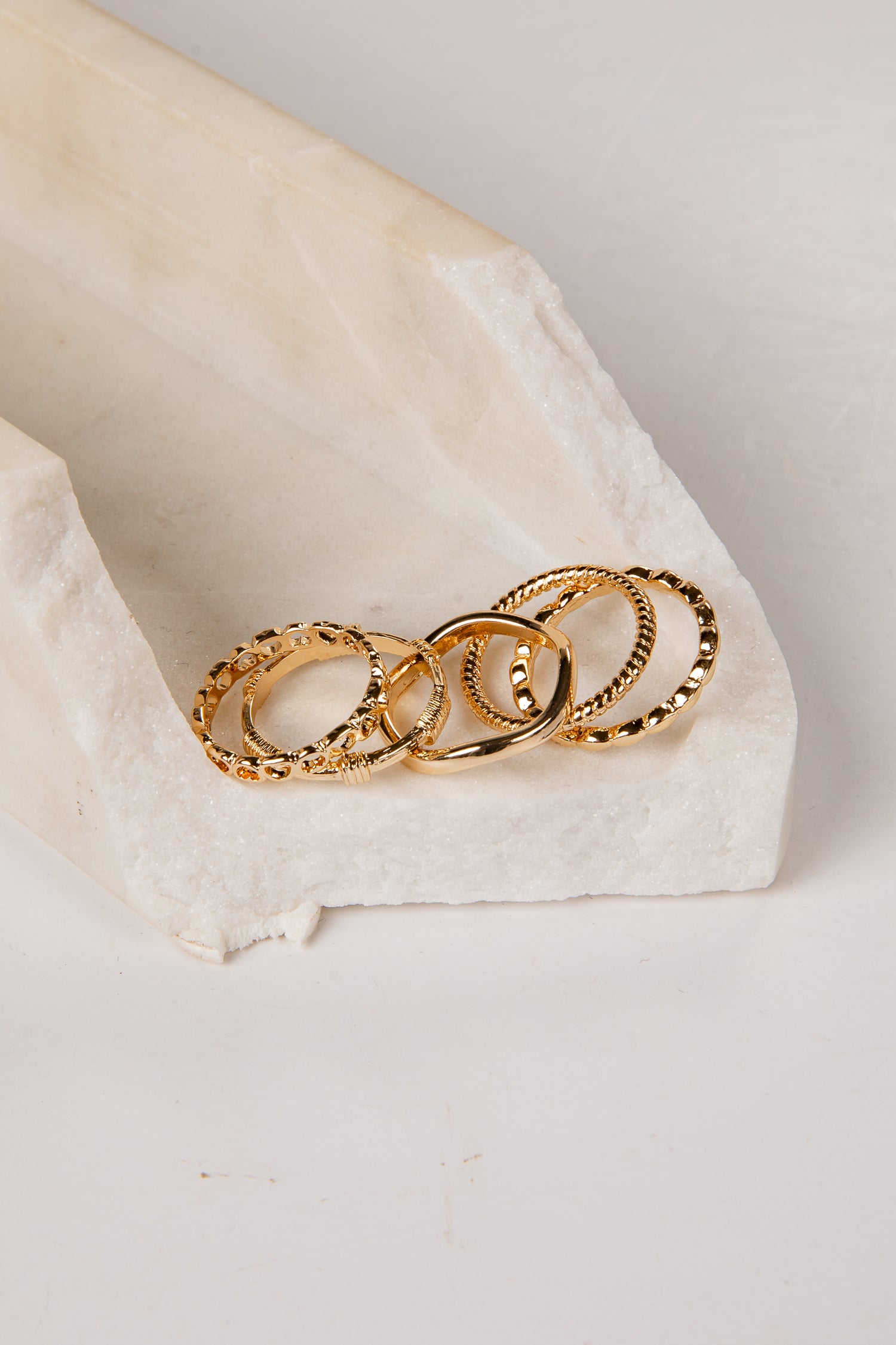 Three gold rings stacked on a white stone surface