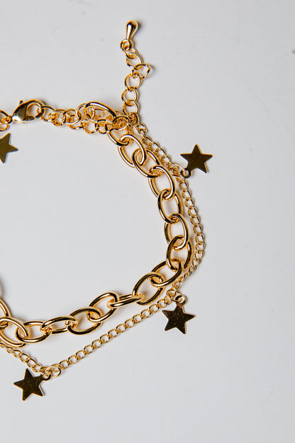 Gold chain bracelet with star charms on a light gray background