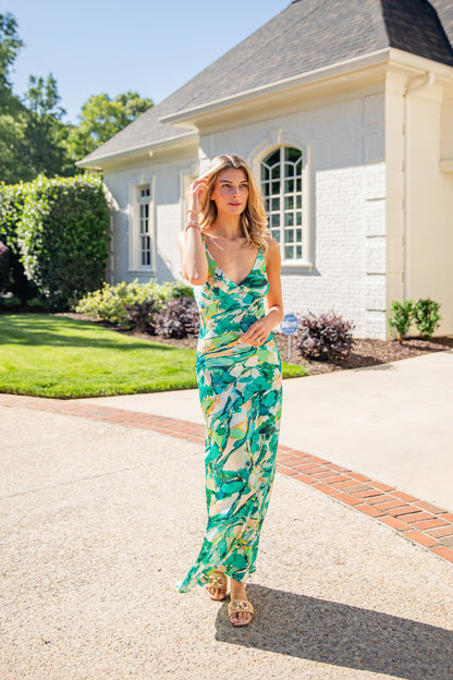 Woman in a green floral dress standing on a driveway with a house in the background