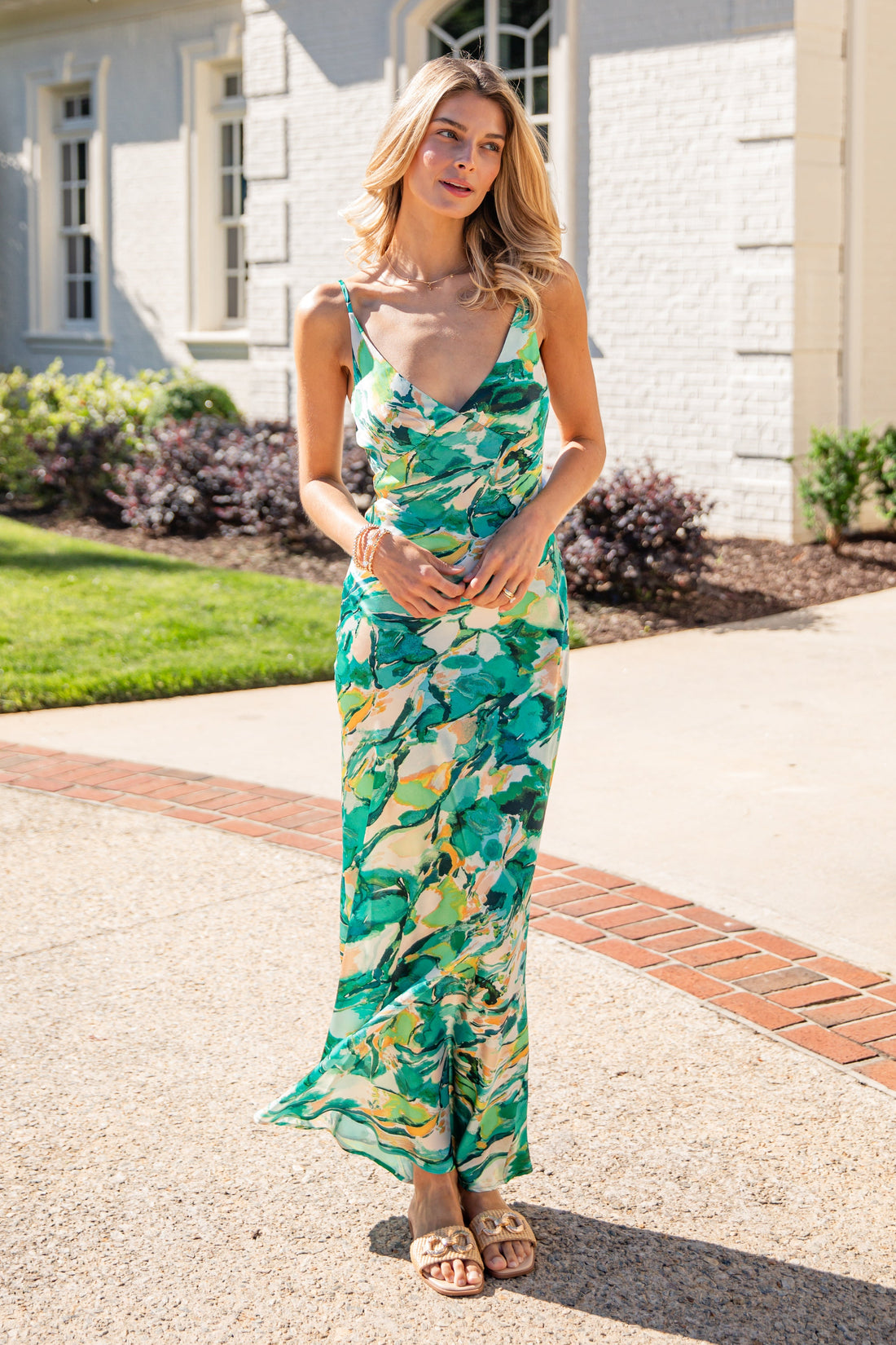 Woman in a floral dress standing on a driveway with a house in the background