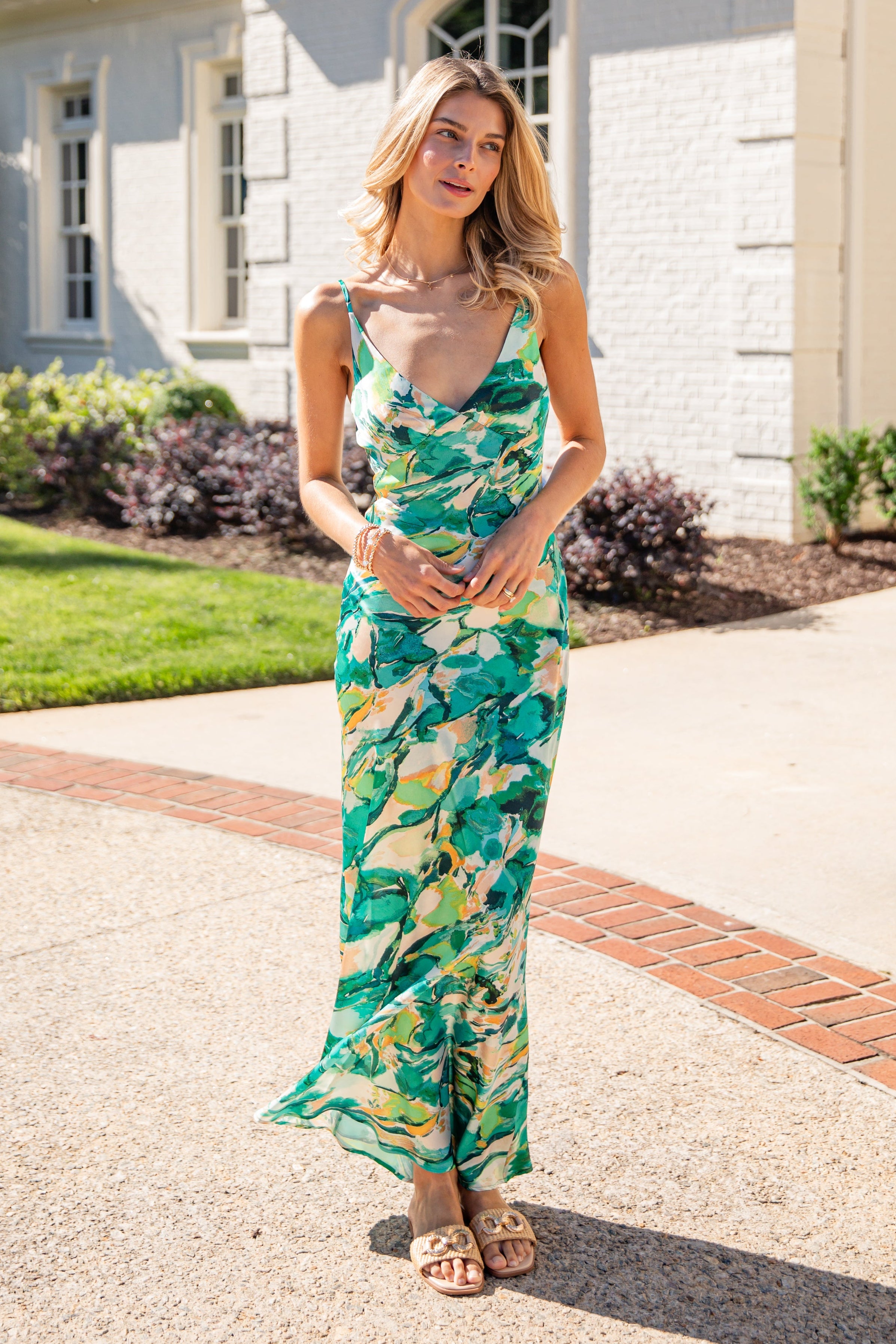 Woman in a floral dress standing on a driveway with a house in the background