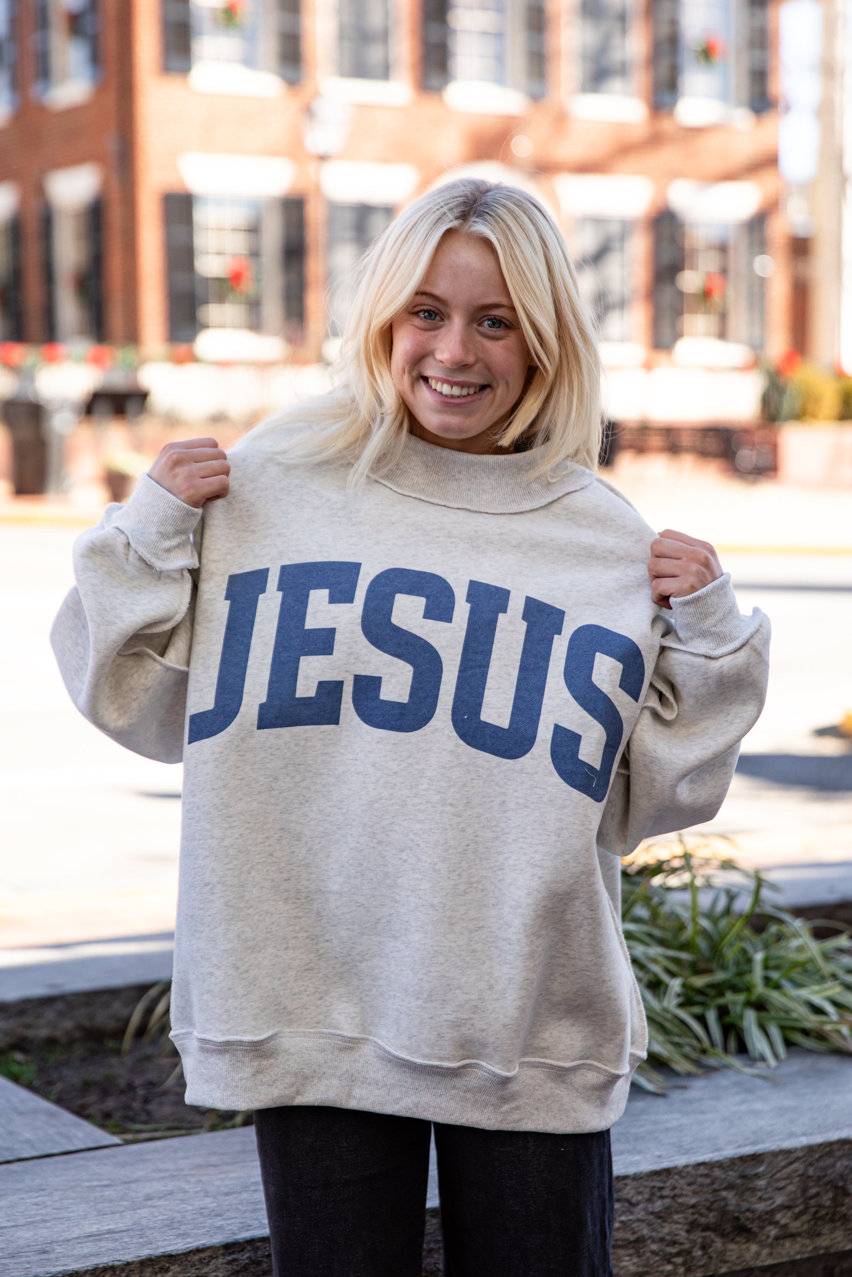 Person wearing a beige sweatshirt with &