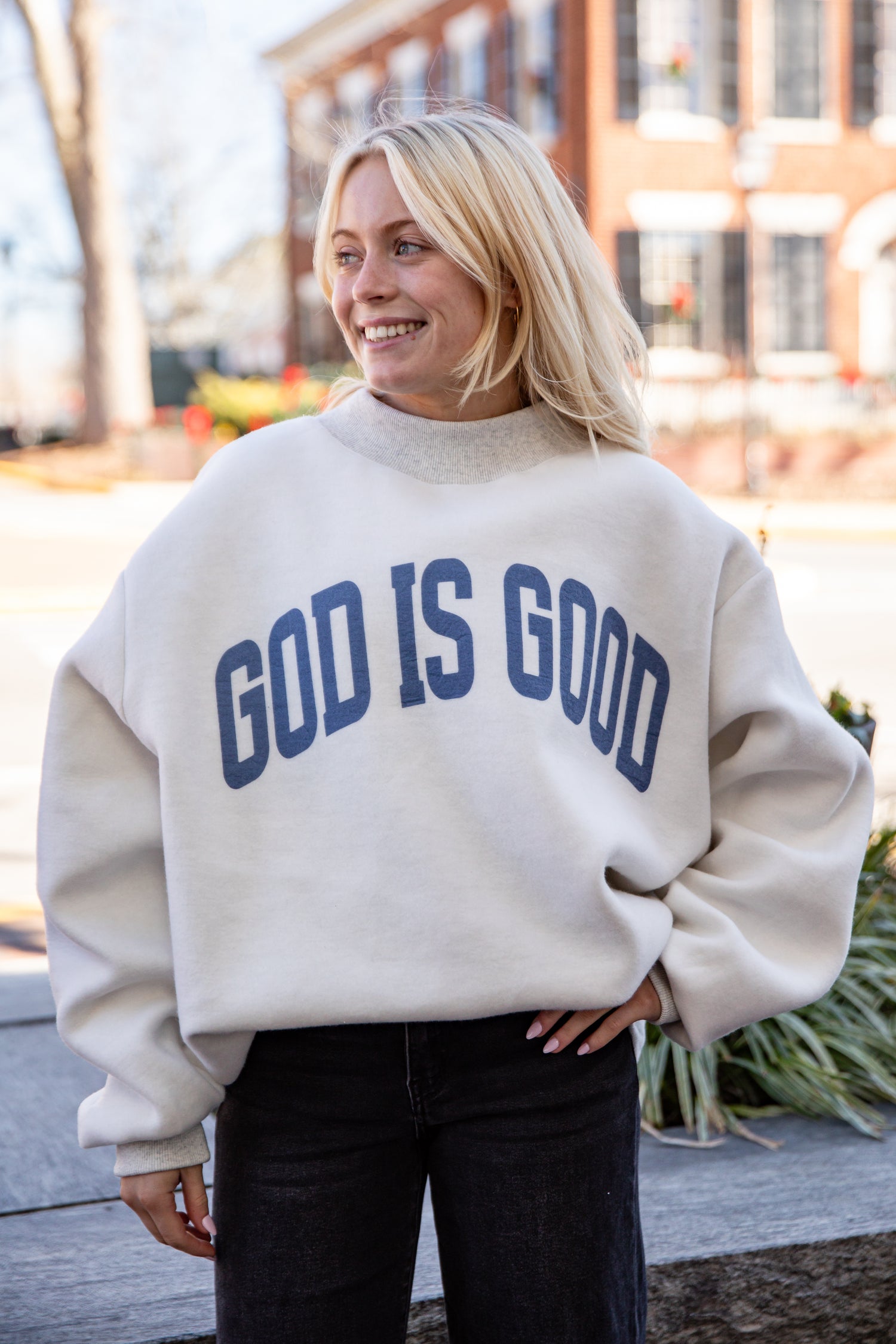 Person wearing a beige sweatshirt with &