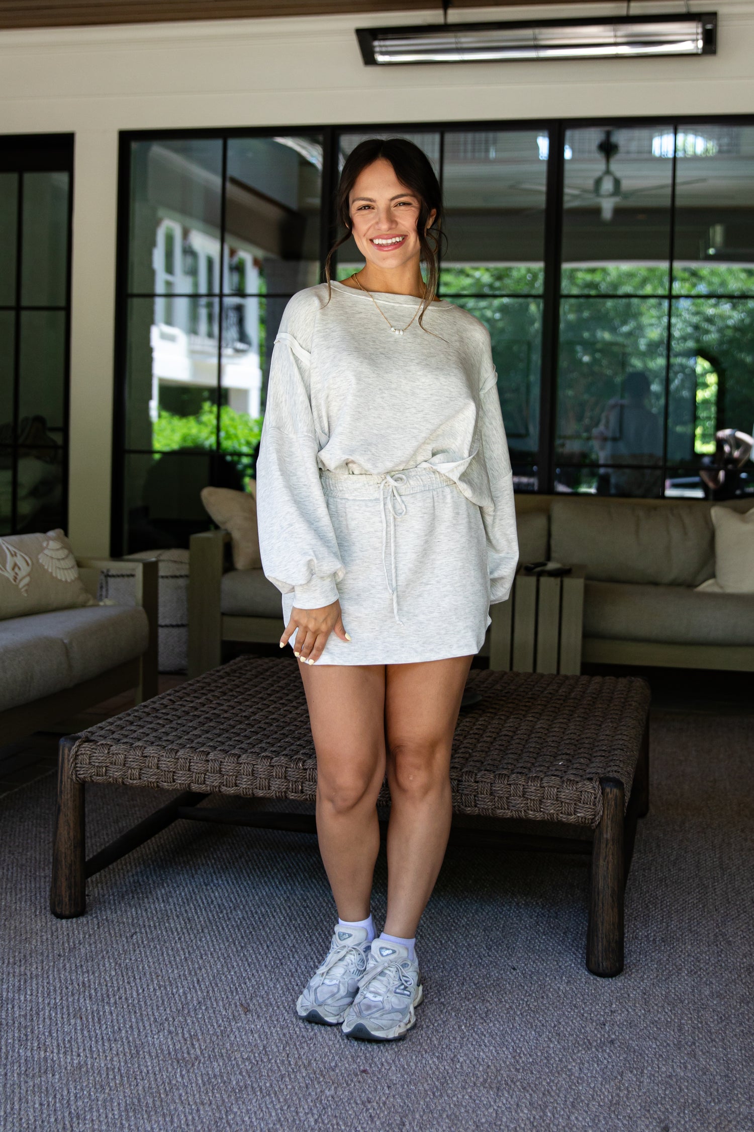 Woman in a white outfit standing in a living room.