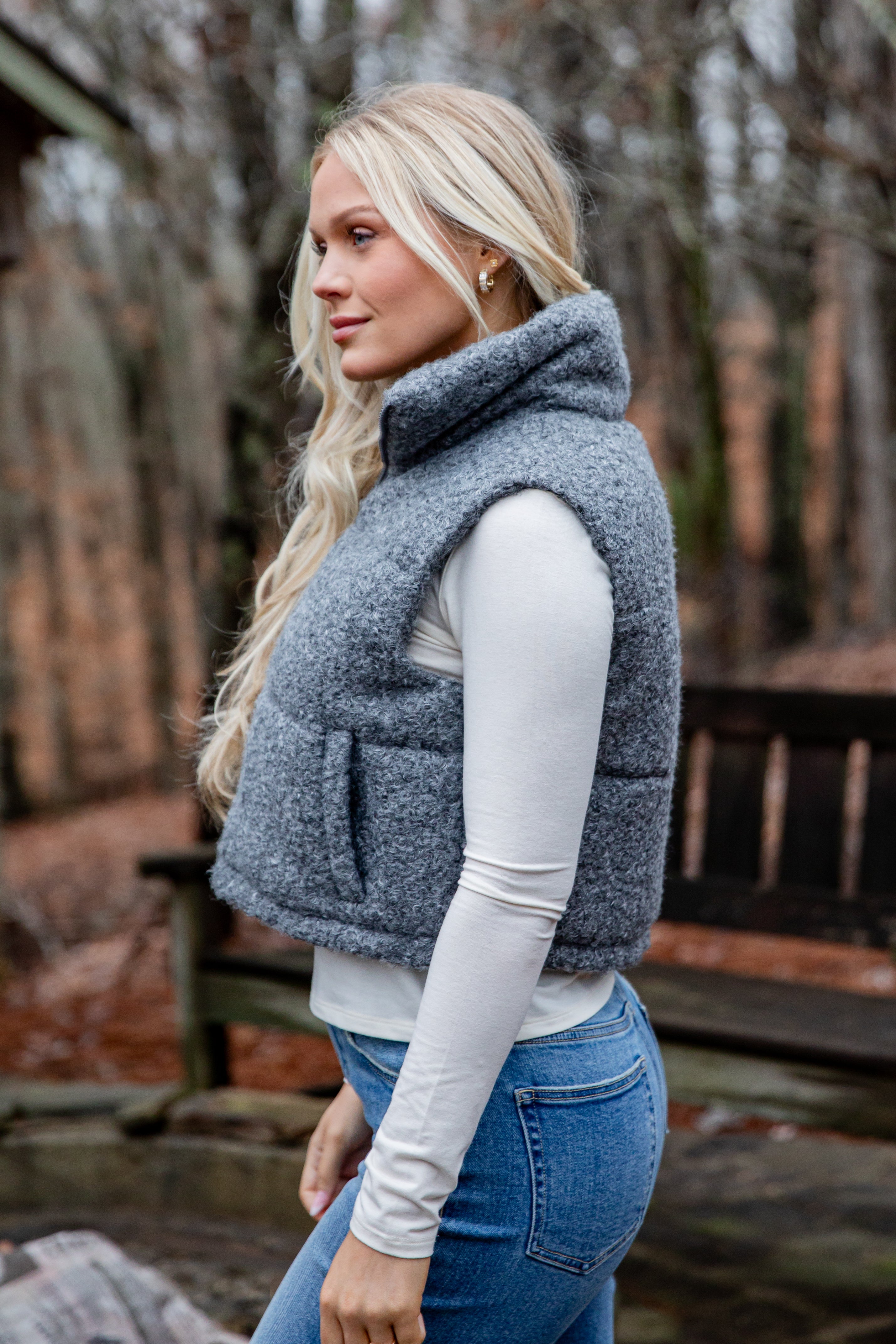 Woman wearing a gray fleece vest outdoors with a blurred background