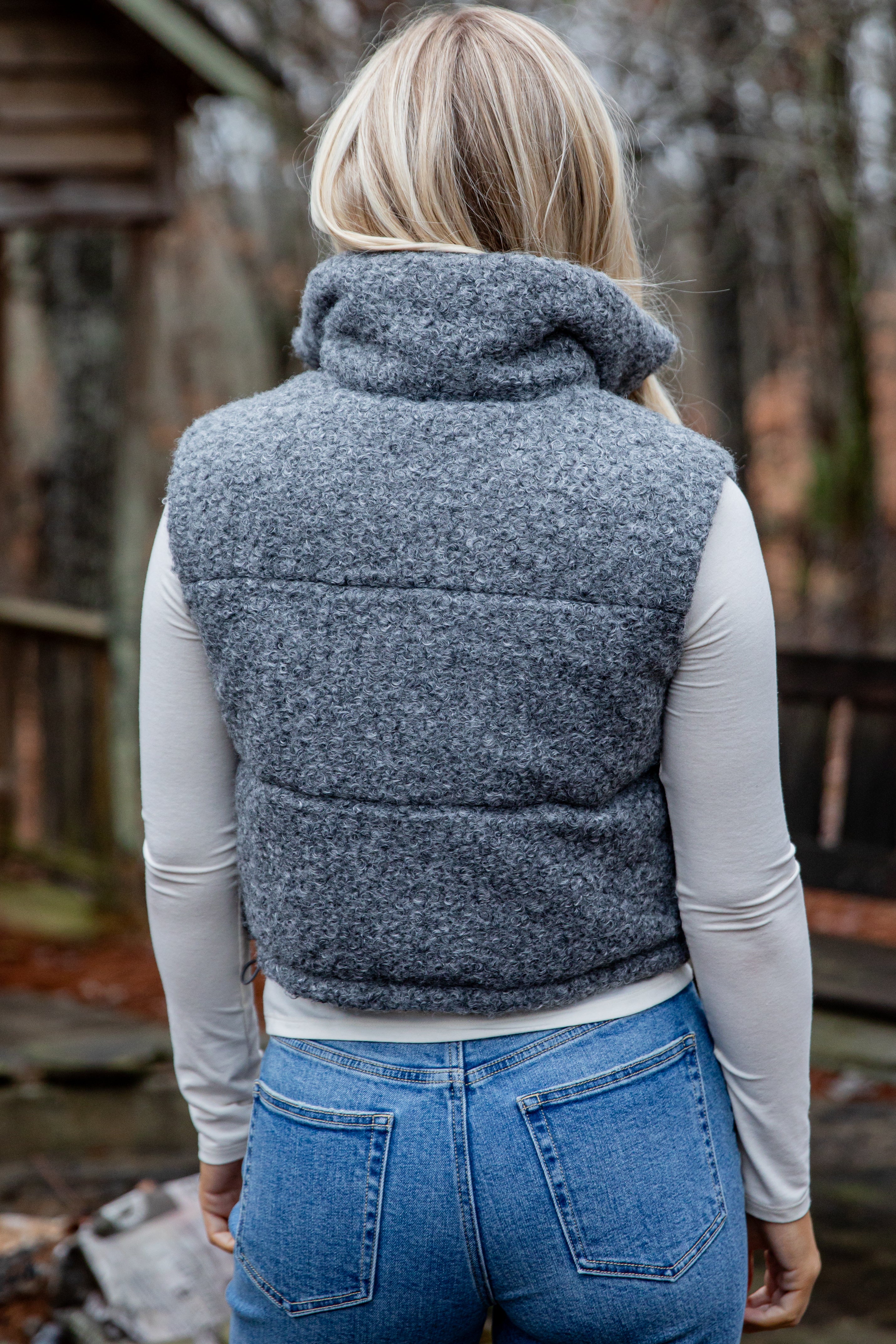 Person wearing a gray puffer vest outdoors with a blurred background