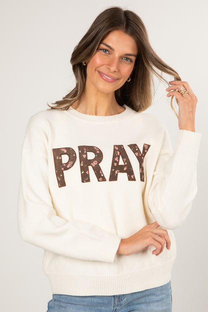 Woman wearing a cream sweater with &