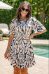 Woman wearing a black and white patterned dress standing by a pool.
