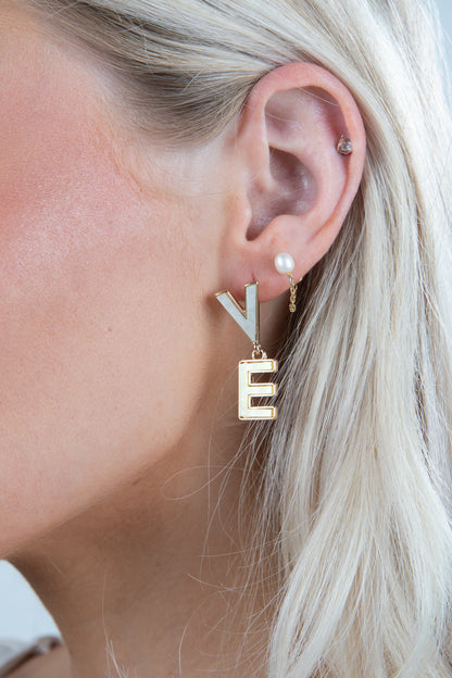 Close-up of a person wearing gold letter &