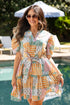Woman in a colorful dress standing by a pool with greenery in the background