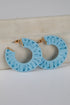 Light blue hoop earrings with ruffled edges on a light gray background