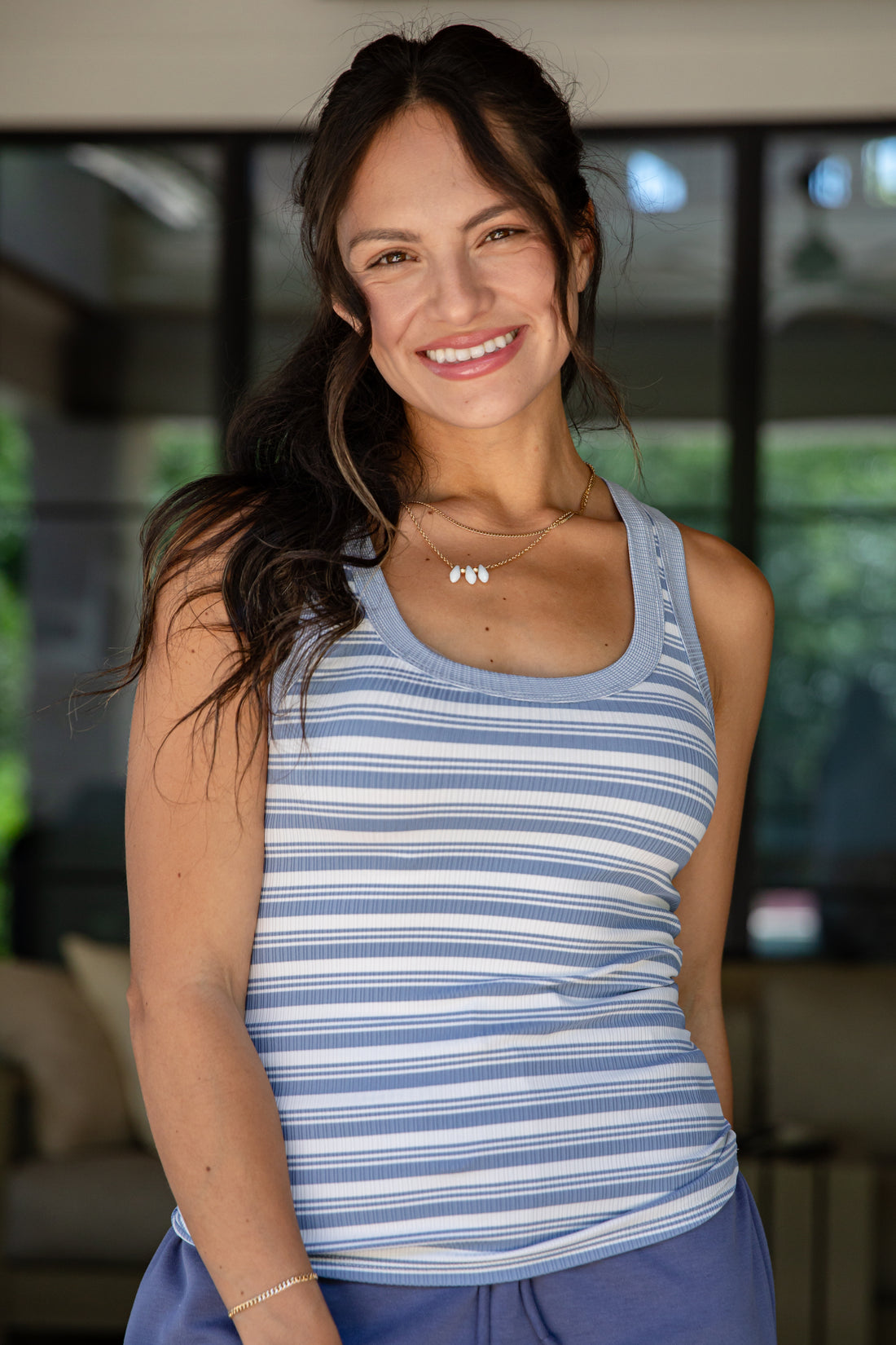 Woman wearing a blue striped tank top with a blurred indoor background