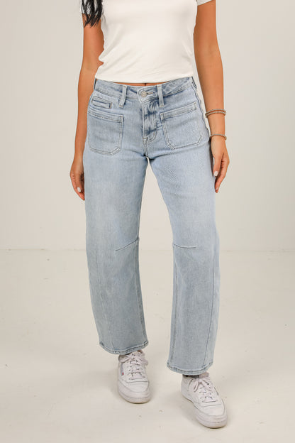 Person wearing light blue jeans and white sneakers on a plain background