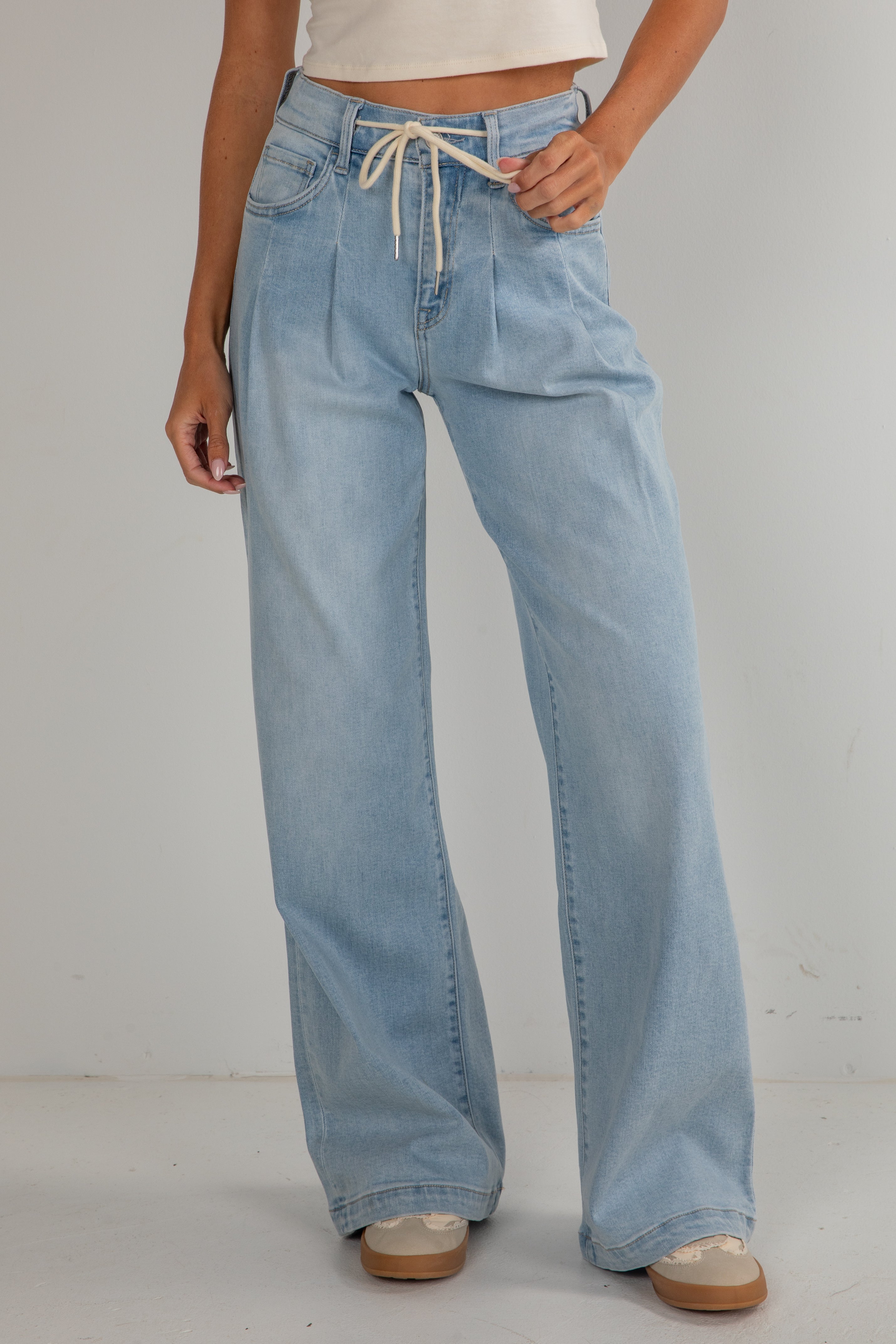 Light blue jeans worn by a person on a plain background