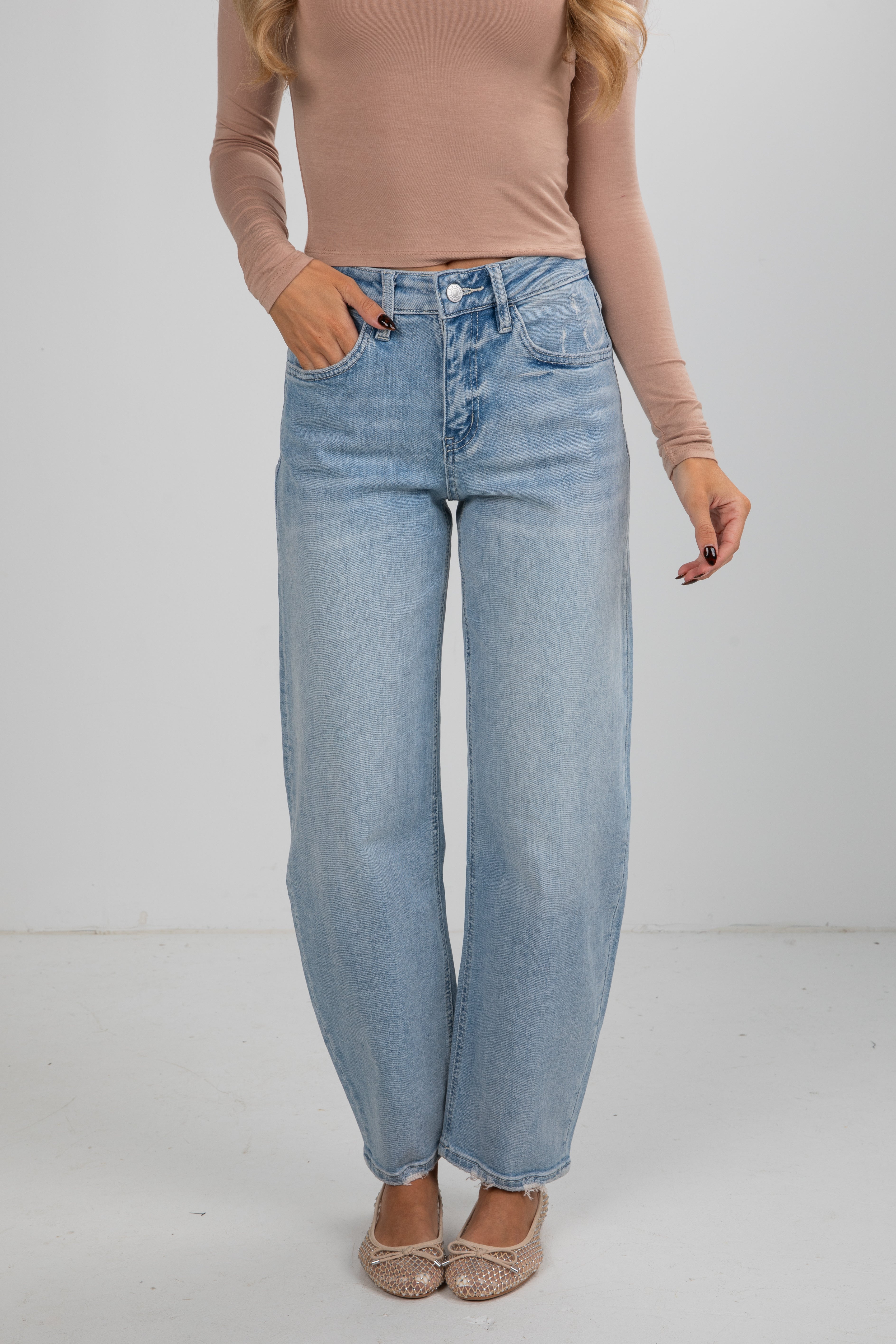 Person wearing light blue jeans and a beige top on a plain background