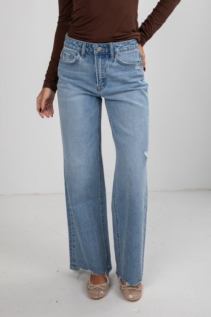 Person wearing light blue jeans and a brown top on a white background