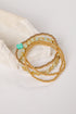 Set of gold and green beaded bracelets on a light background