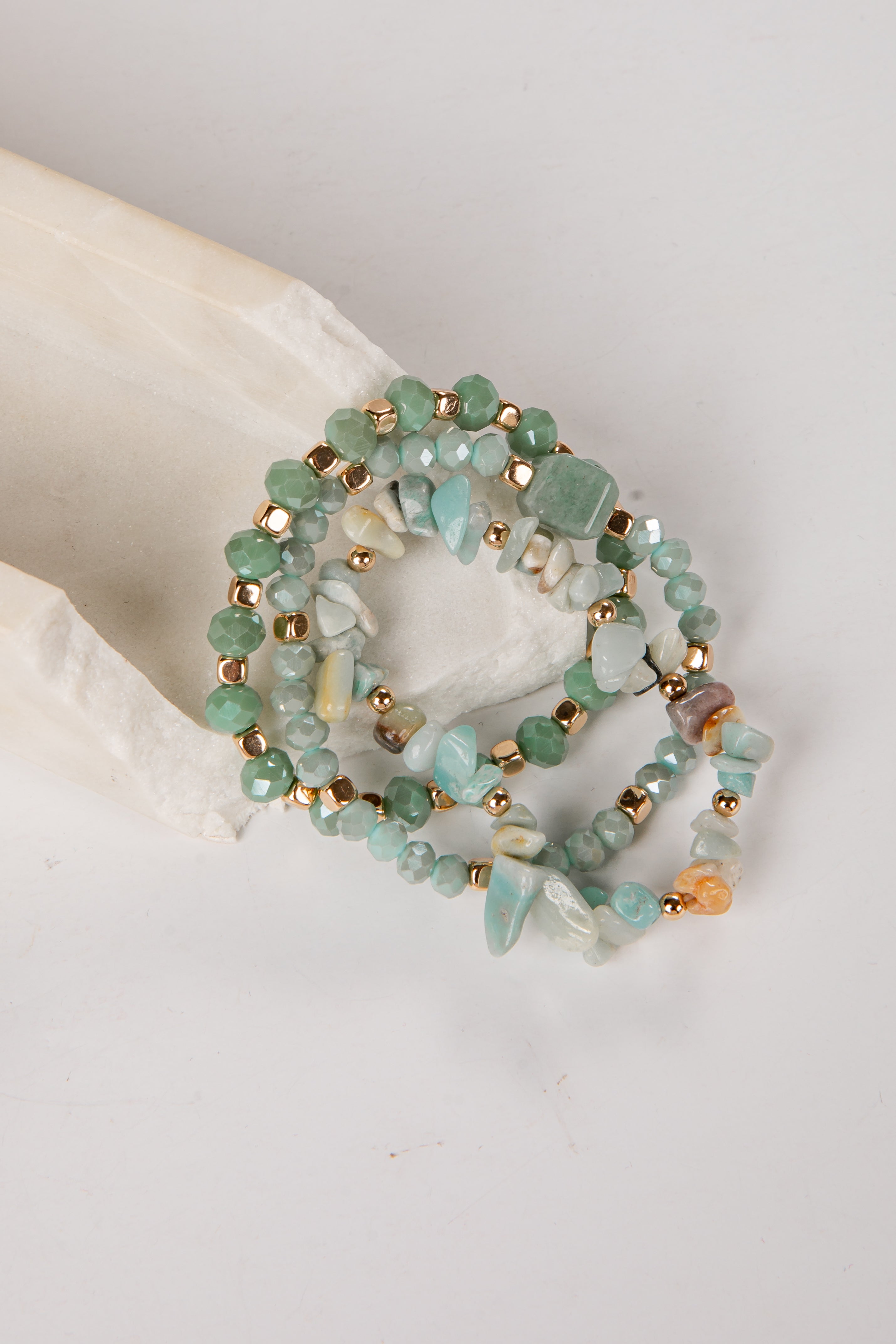 Set of three beaded bracelets with gold accents on a light background