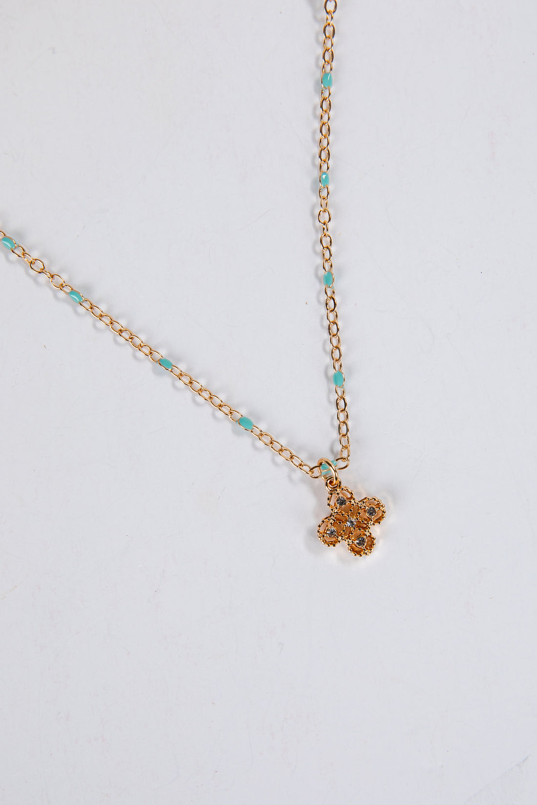Gold necklace with a small pendant on a light gray background