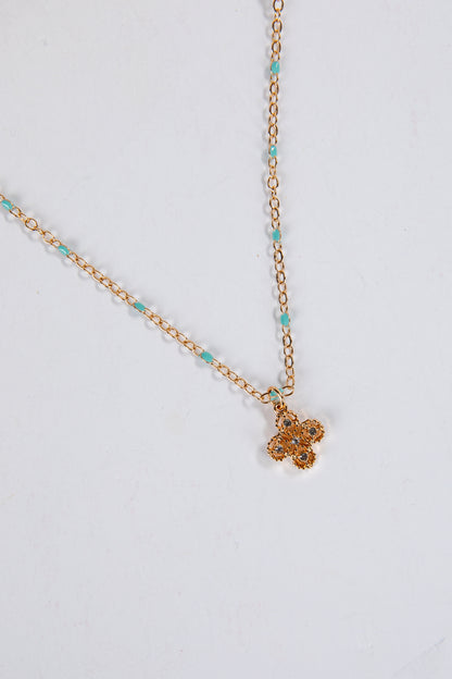 Gold necklace with a small pendant on a light gray background