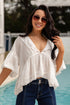 Woman wearing a white blouse and sunglasses by a pool