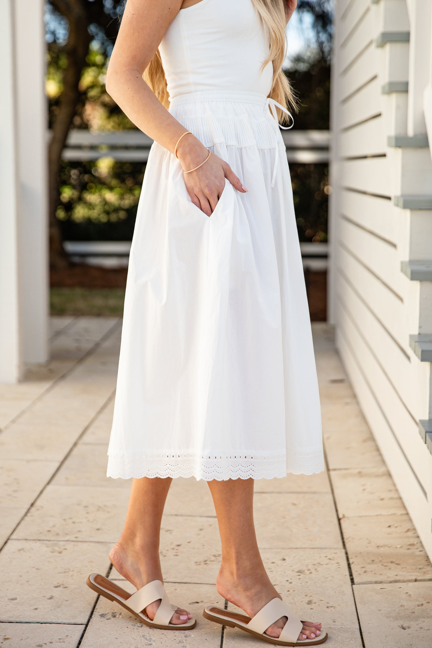Woman wearing a white skirt standing on a wooden deck.