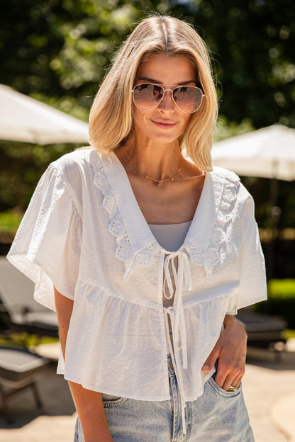 Woman wearing a white lace top and sunglasses outdoors