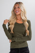 Woman wearing an olive green long-sleeve top against a plain background