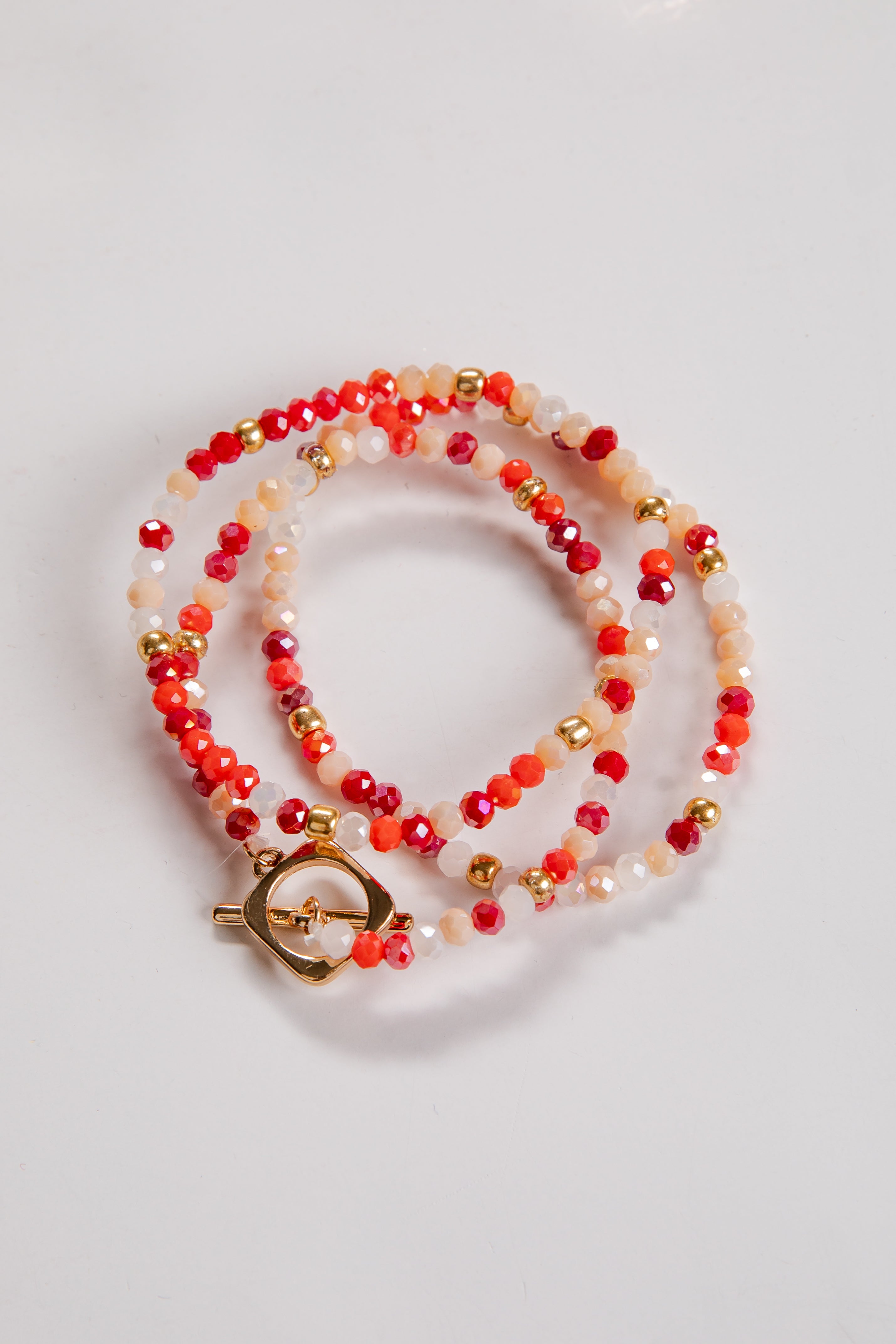 Beaded bracelet with orange, gold, and white beads on a light gray background