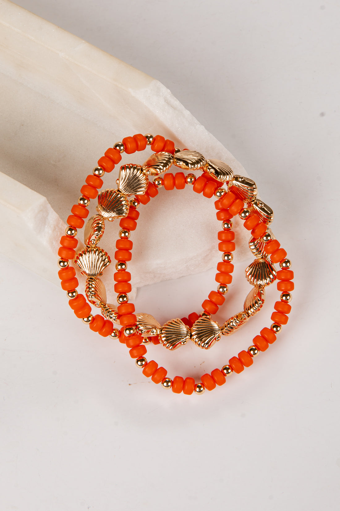 Orange beaded bracelet with gold accents on a light background