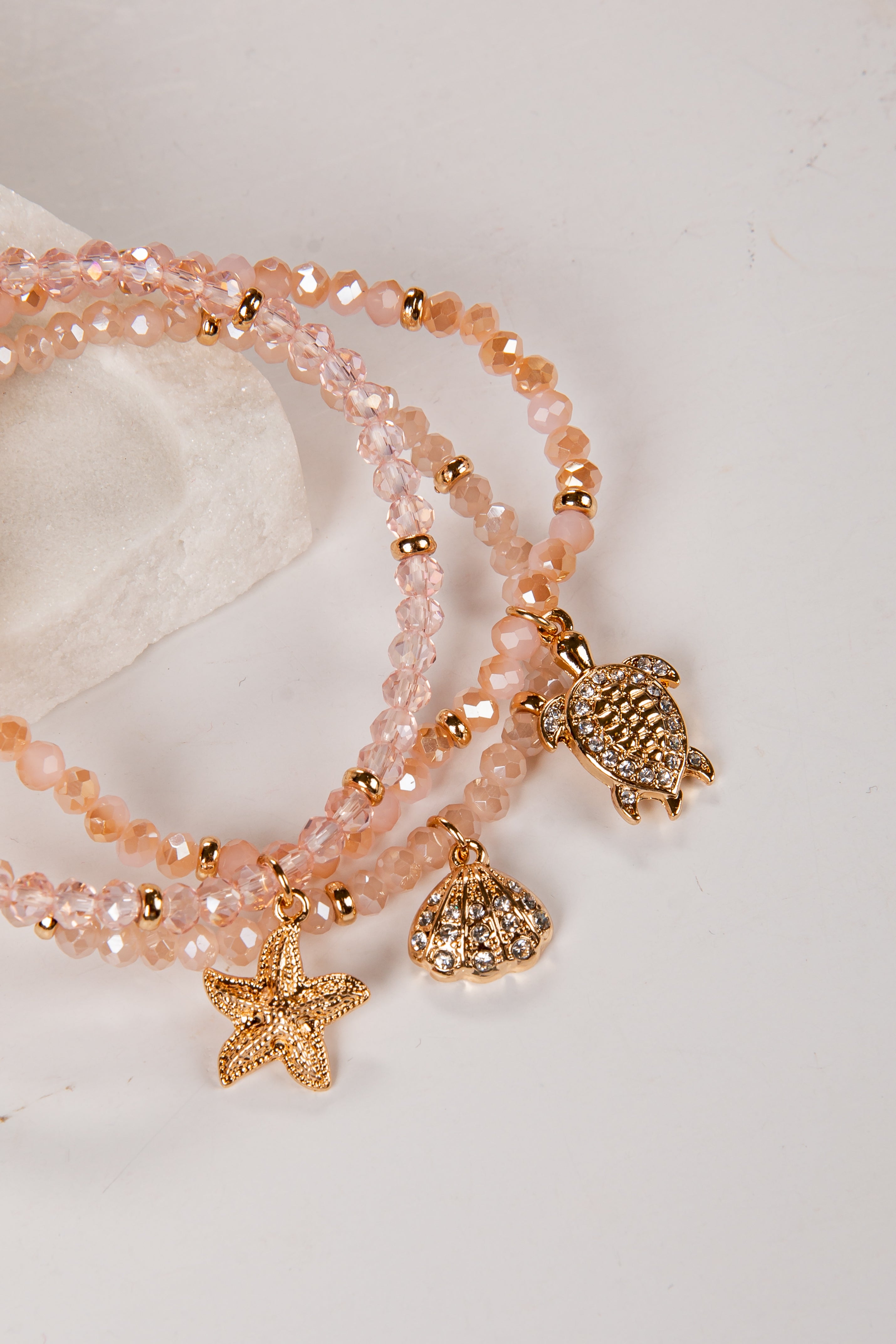 Set of beaded bracelets with turtle and starfish charms on a light background