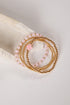 Set of gold and pink beaded bracelets on a white shell