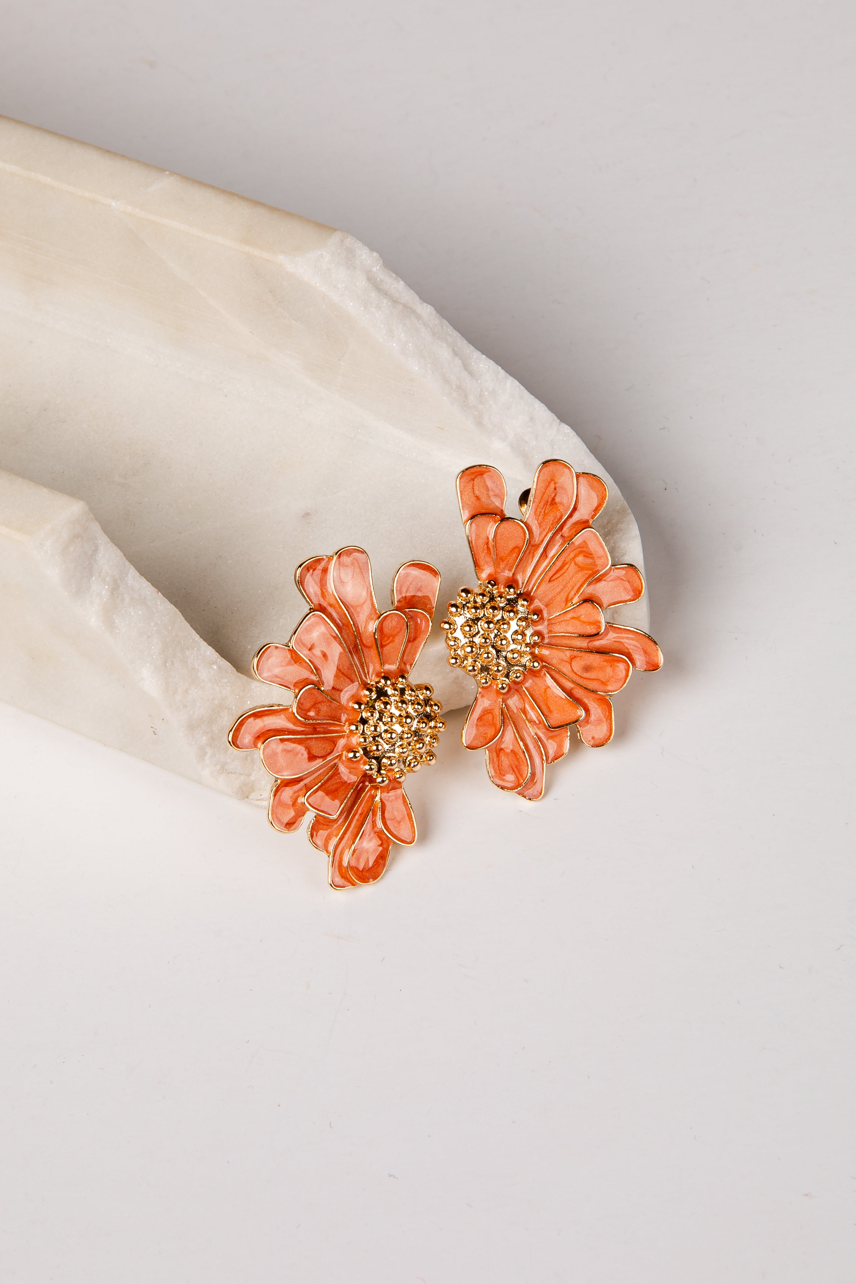 Floral earrings with gold centers on a light background