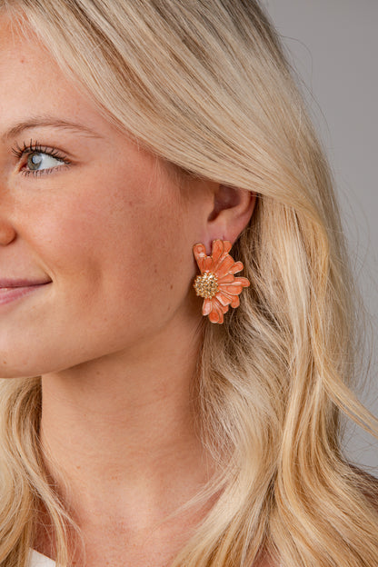 Close-up of a woman wearing a floral earring with a neutral background